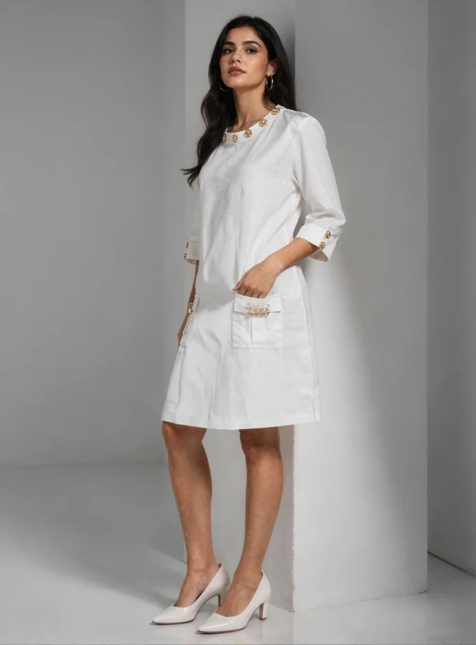 Esme — model wearing the white denim A-line dress with gold neckline and pocket detailing