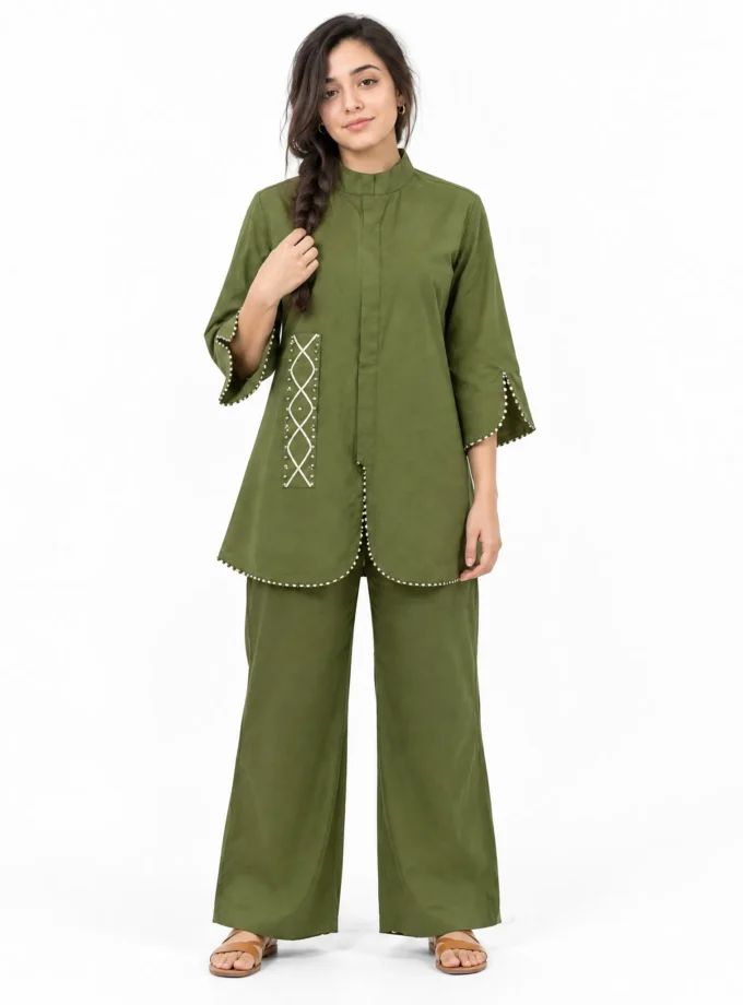 Model wearing the NOLA military green co-ord set — mandarin collar high-low shirt with black & white lace detailing and the matching wide-leg trousers with a curved hem
