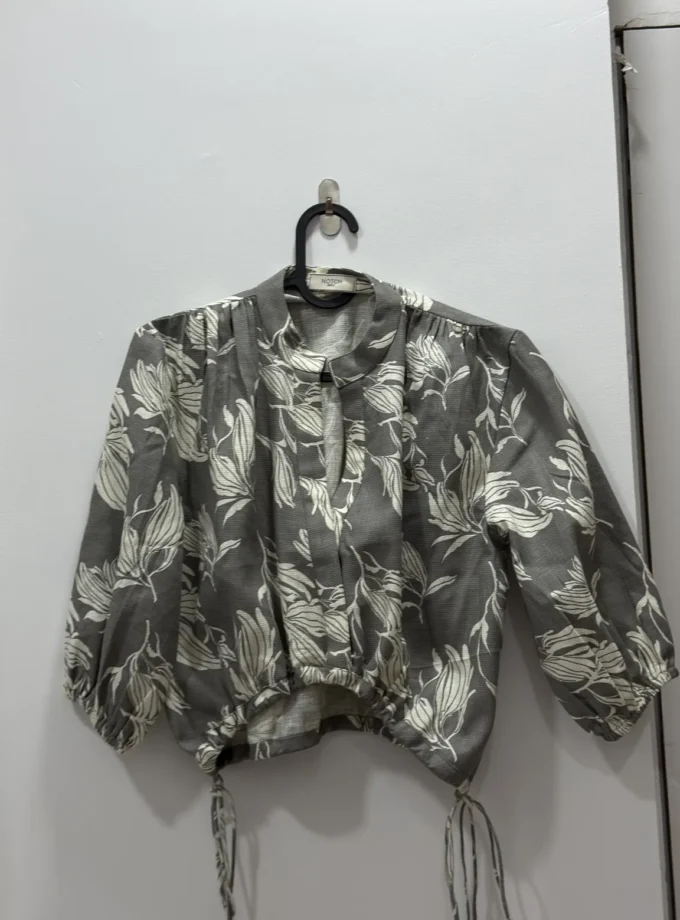 Stone grey floral printed drawstring pull crop top shown alone on a hanger