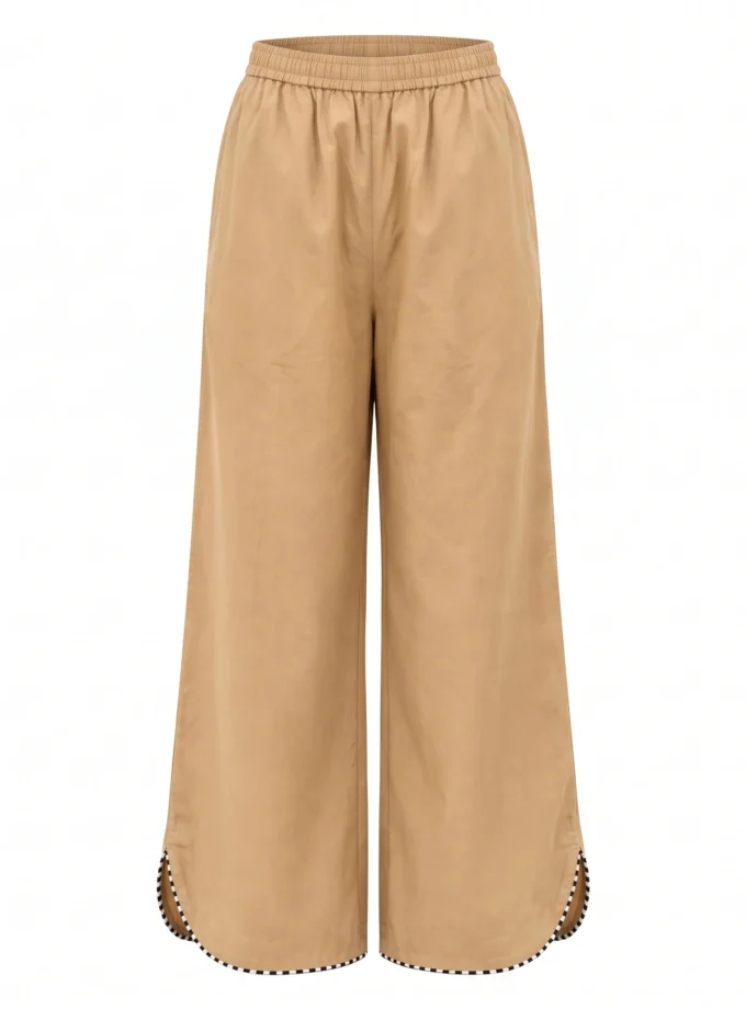 Zoreille biscuit beige cotton trousers with black and white lace detailing and a curved hem, shown alone on an invisible mannequin